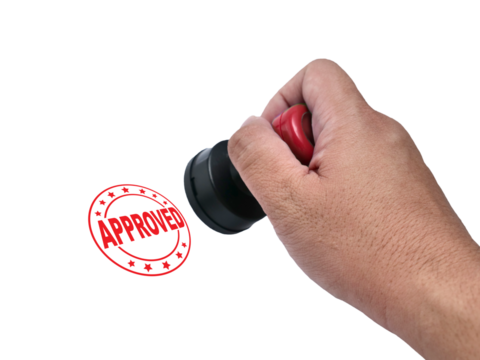 Approved, hand holding red handled round rubber stamp, top view isolated on white