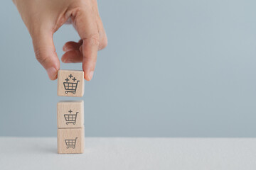 For increasing sales volume, marketing strategy, business growth concept. Hand arranged stack of wooden cube blocks with different size of shopping cart and plus sign including copy space