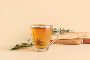 Glass cup of hot rosemary tea on beige background