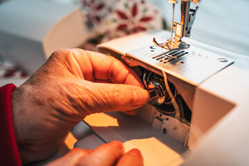 detail fingers of seamstress preparing the sewing machine before starting the work day
