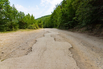 After an earthquake and a strong storm, the remains of an asphalt road in the mountains. Closed road. Destroyed asphalt road. Broken asphalt, crack and landslides.
