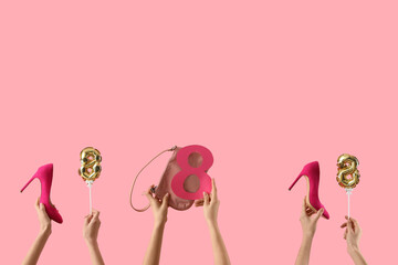 Female hands with balloons in shape of figure 8, high heel shoes and handbag on pink background....
