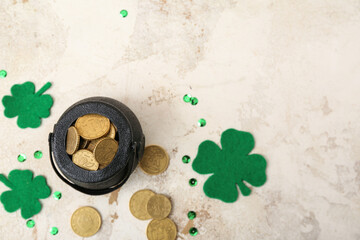 Leprechaun pot with golden coins and clover leaves on beige grunge background. St. Patrick's Day celebration