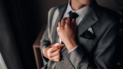 Man groom fixing his tie.