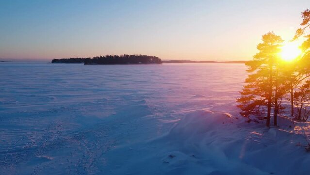 Aerial view circling over snowy sea ice, winter sunset in the Finnish archipelago