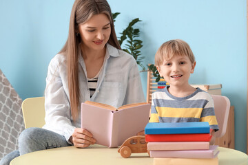 Fototapeta premium Mother with her son reading books at table in children's room