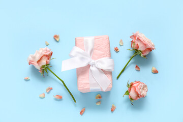 Gift box with roses and petals on blue background