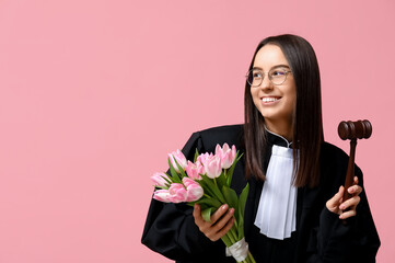 Young female judge with tulips on pink background. Women's Day celebration