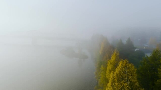Aerial view of fall colored trees along a river, misty, autumn sunrise in the Nordics