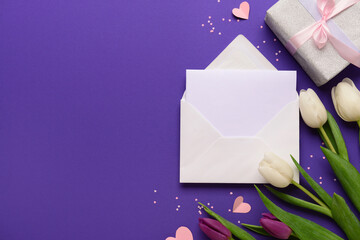 Envelope with blank card, gift box and tulip flowers on purple background. International Women's Day celebration