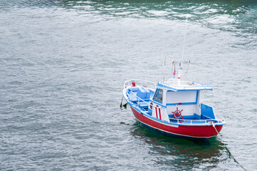 A red and blue wooden boat moored at the port