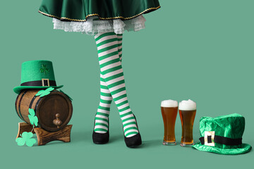 Woman in waitress costume with glasses of beer, leprechaun's hats, barrel and clovers on green...