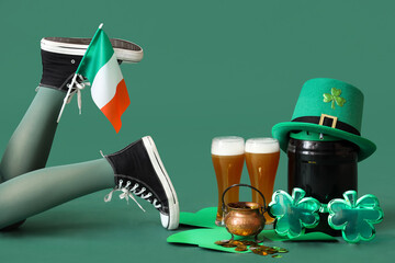 Female legs in stockings with glasses of beer, Irish flag, barrel and leprechaun's hat on green...