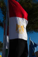 Close up photo of the narrow Egyptian flag. Flagpole with the symbol of an African country flutters in the wind