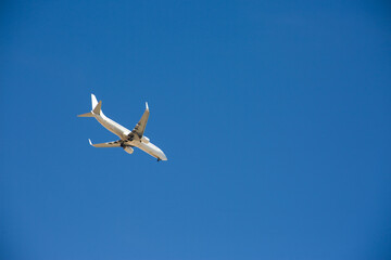 White airplane with extended landing gear preparing to land at the airport against the blue sky