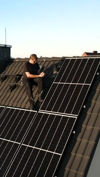 Man Checking Solar Panels on Top of the Roof of a Single-Family Home