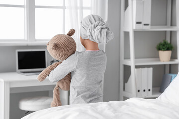 Little girl after chemotherapy with toy bear in clinic, back view. International Childhood Cancer...