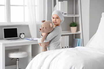 Little girl after chemotherapy with toy bear in clinic. International Childhood Cancer Day