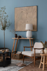 Interior design of rural style living room with white armchair, wooden shelf, olive tree, paintings, decorations and elegant accessories. Template. Blue wall. 