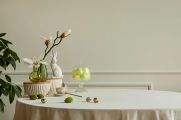 Schilderijen op glas Minimalist composition of easter dining room interior with copy space, gray easter bunny sculpture, colorful eggs, vase with magnolia, beige wall with stucco and personal accessories. Home decor.  © FollowTheFlow