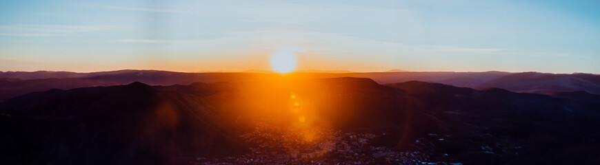 Capturing the breathtaking beauty of a vibrant orange and purple sunset over a majestic mountain during a serene summer evening