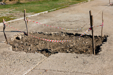 Bad automobile, pedestrian road with a large pit and a signal fence.