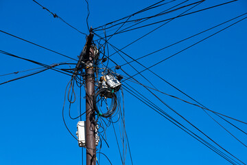 Internet, wires and cable on a distribution pole on the street against the blue sky.
