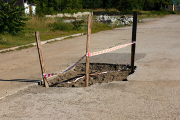Bad automobile, pedestrian road with a large pit and a signal fence.