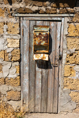 An old rusty mailbox on an old front door with peeling paint and a brick wall. Concept