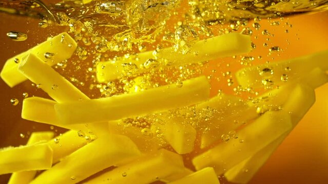 Super Slow Motion of Falling French Fries into Oil. Underwater Composition of Splashing Potatoes Fries. Filmed on High Speed Cinema Camera, 1000 fps. Speed Ramp Effect.
