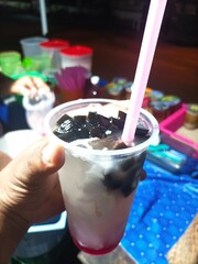 Young coconut ice is a typical Indonesian drink served in a glass with pieces of black grass jelly...