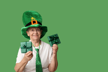 Senior woman in leprechaun hat with gift boxes on green background. St. Patrick's Day celebration