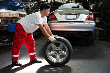 mechanic holding and pushing a tire for fixing in garage