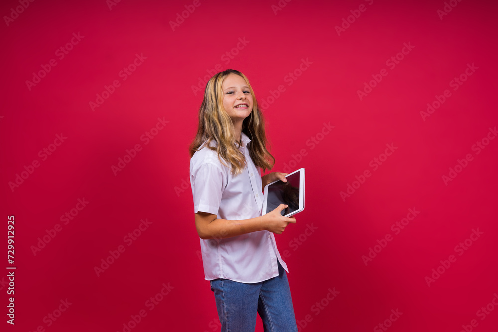 Wall mural online school app. schoolgirl showing tablet computer empty screen over red background. studio shot