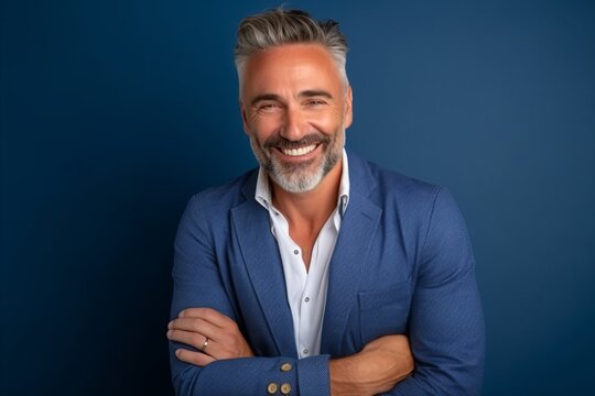 Portrait of a handsome mature man smiling with arms crossed against blue background