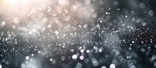 Sparkling silver particles with bokeh creating an abstract background. Festive dust for Christmas and New Year.