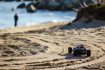 rc car racing on a sandy beach track, person standing nearby