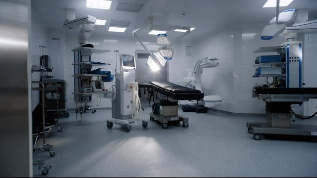 Dolly shot of operation block in modern clinic with advanced equipment ready for surgery. Operating table, LED lamps, life support machine. Bright operating room in hospital or medical facility.