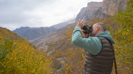 a tourist takes pictures of a beautiful autumn mountain landscape using a camera
