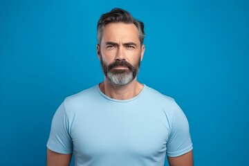 Portrait of serious mature man in blue t-shirt on blue background