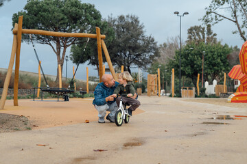 Dad teaches his son riding on bicycle in park. Father and son smile and have fun together