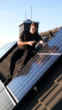 Technician Working on Solar Panels on the Roof of a Single-Family Home