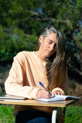 Obraz premium Entrepreneur woman working outdoors writing things down in a planner at a desk