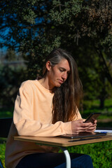 Obraz premium Middle-aged Caucasian woman working from her home garden with a desk and cell phone