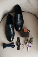 men's accessories of the groom black leather shoes, a watch, perfume and two wedding rings