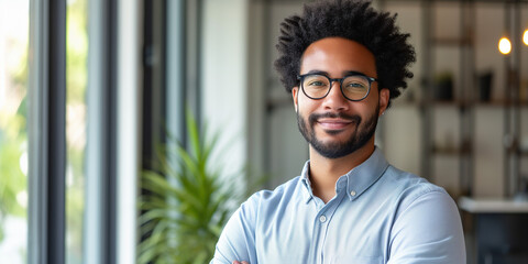 Cheerful young man with afro hair and glasses, wearing a blue shirt, radiates positivity in an office