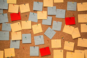 Photo of different colorful memo papers attached with pins to the wooden board. High quality photo
