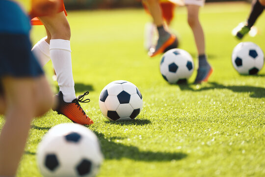 Boys kick football balls. Children attending outdoor soccer class. School children running and kicking balls on summer training camp. Football soccer children training class. Kids practicing football