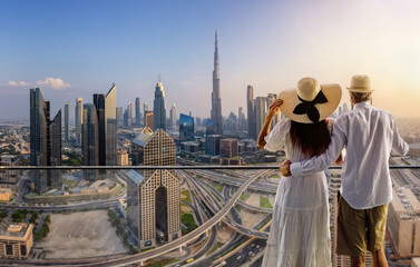 A couple on holidays enjoys the panoramic view over the city skyline of Dubai, UAE, during sunset time