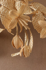 Fototapeta na wymiar Decoration of straw on a beige background. Branch with leaves and flowers is made of straw. Decor. Closeup